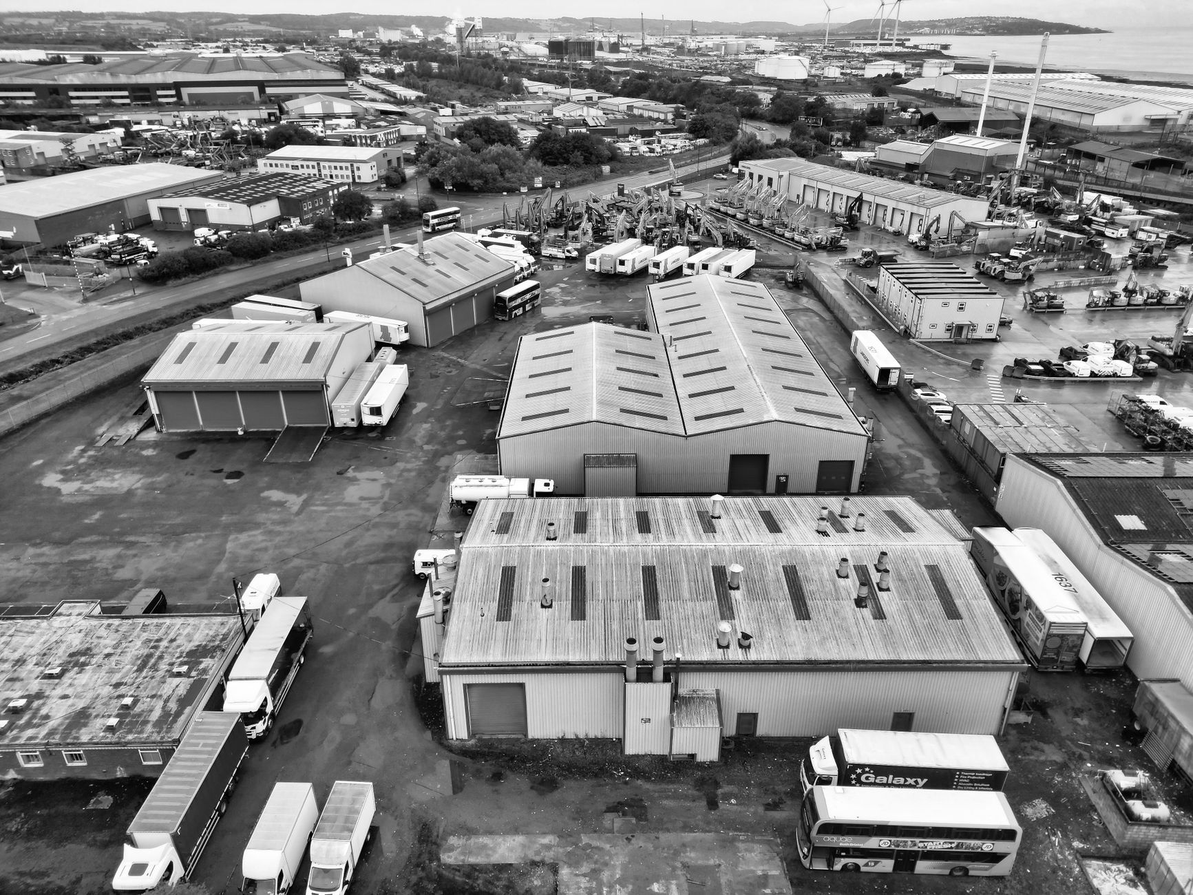 A monochrome aerial shot of an industrial area in England with warehouses and trucks.