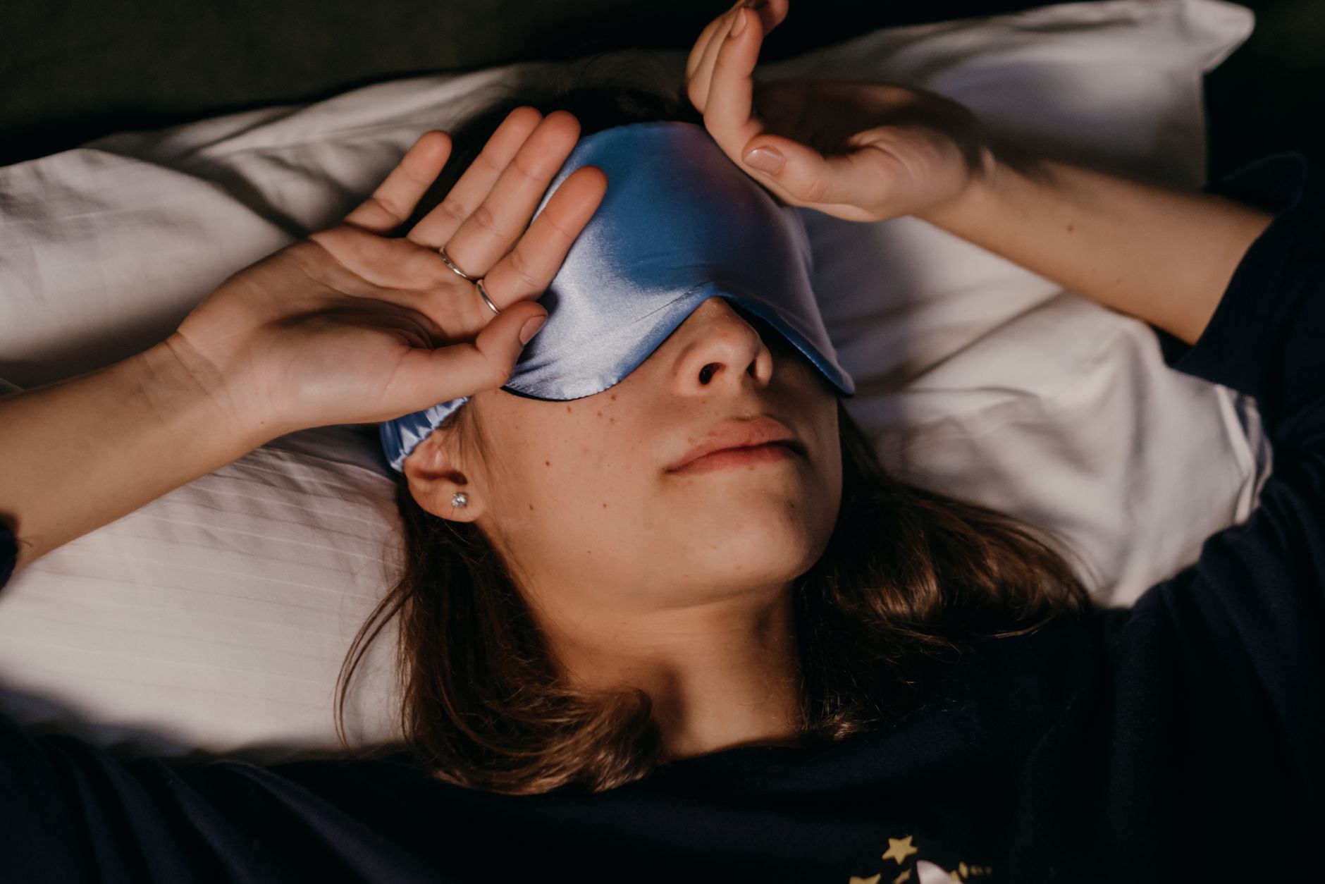 A woman peacefully resting with a sleep mask in a cozy indoor setting.