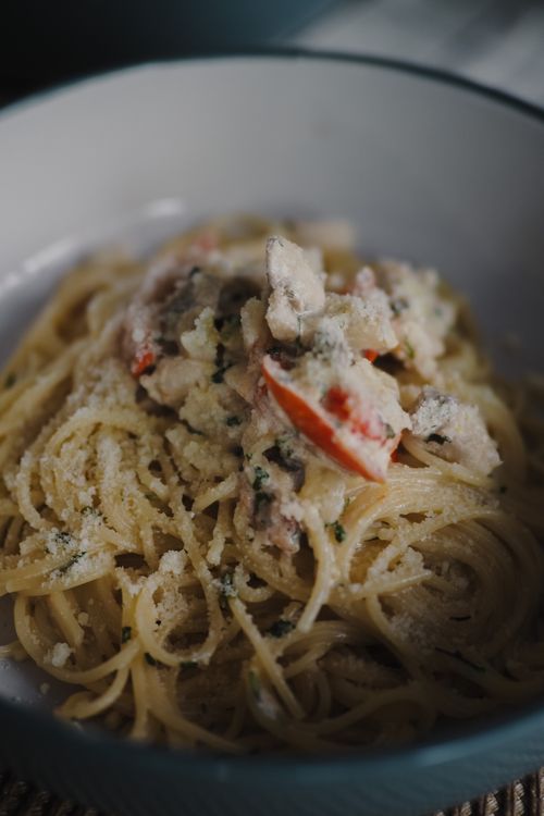 Free Delicious spaghetti topped with creamy sauce and parmesan cheese in a white bowl. Stock Photo