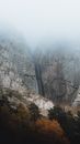 Clouds and Fog Covering Rocky Mountain with Waterfall