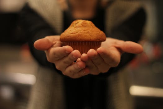 Close-up of hands holding a freshly baked muffin, perfect for bakery promotions.