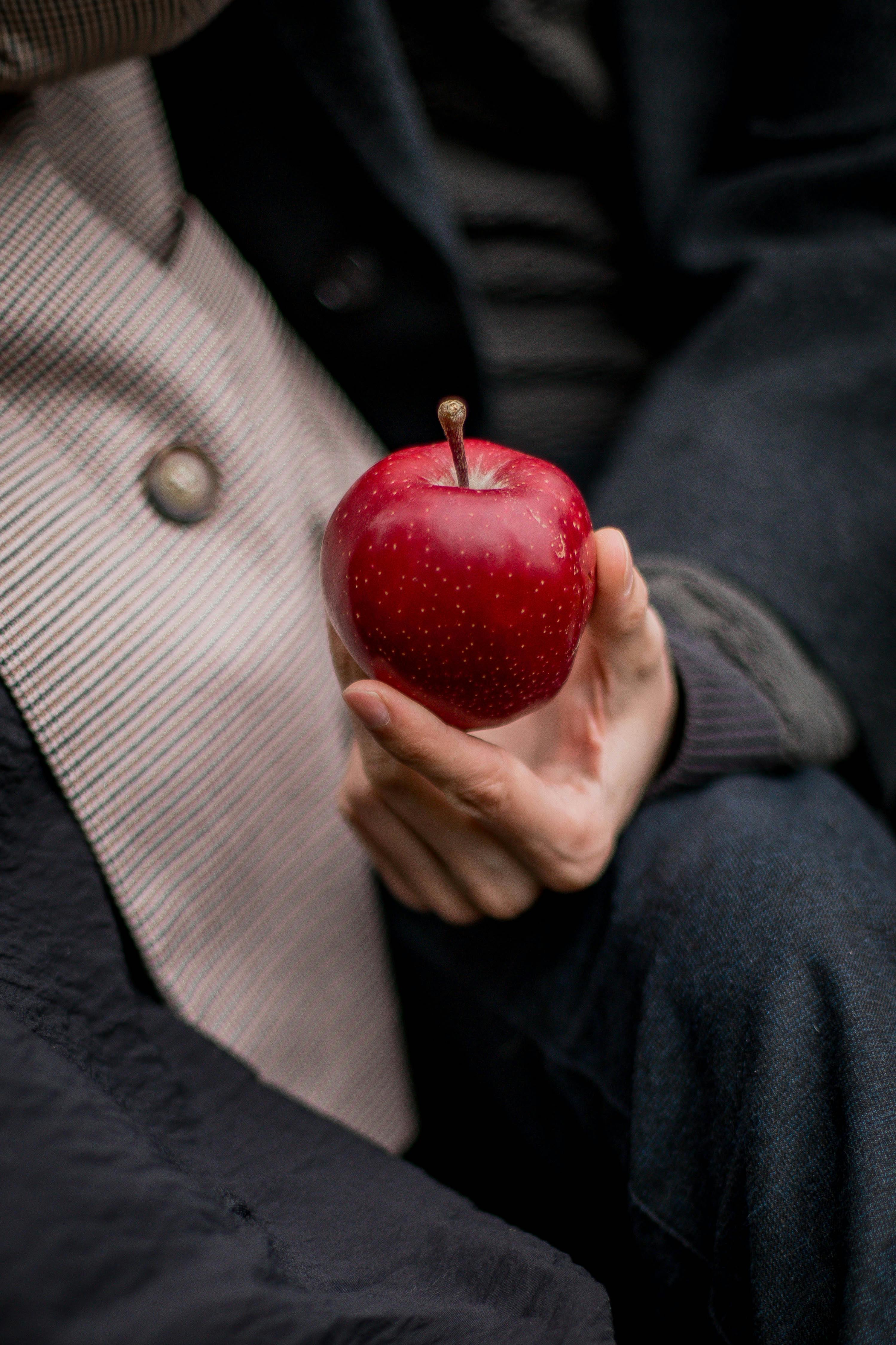 A detailed shot of a hand holding a red apple, conveying a sense of autumn.