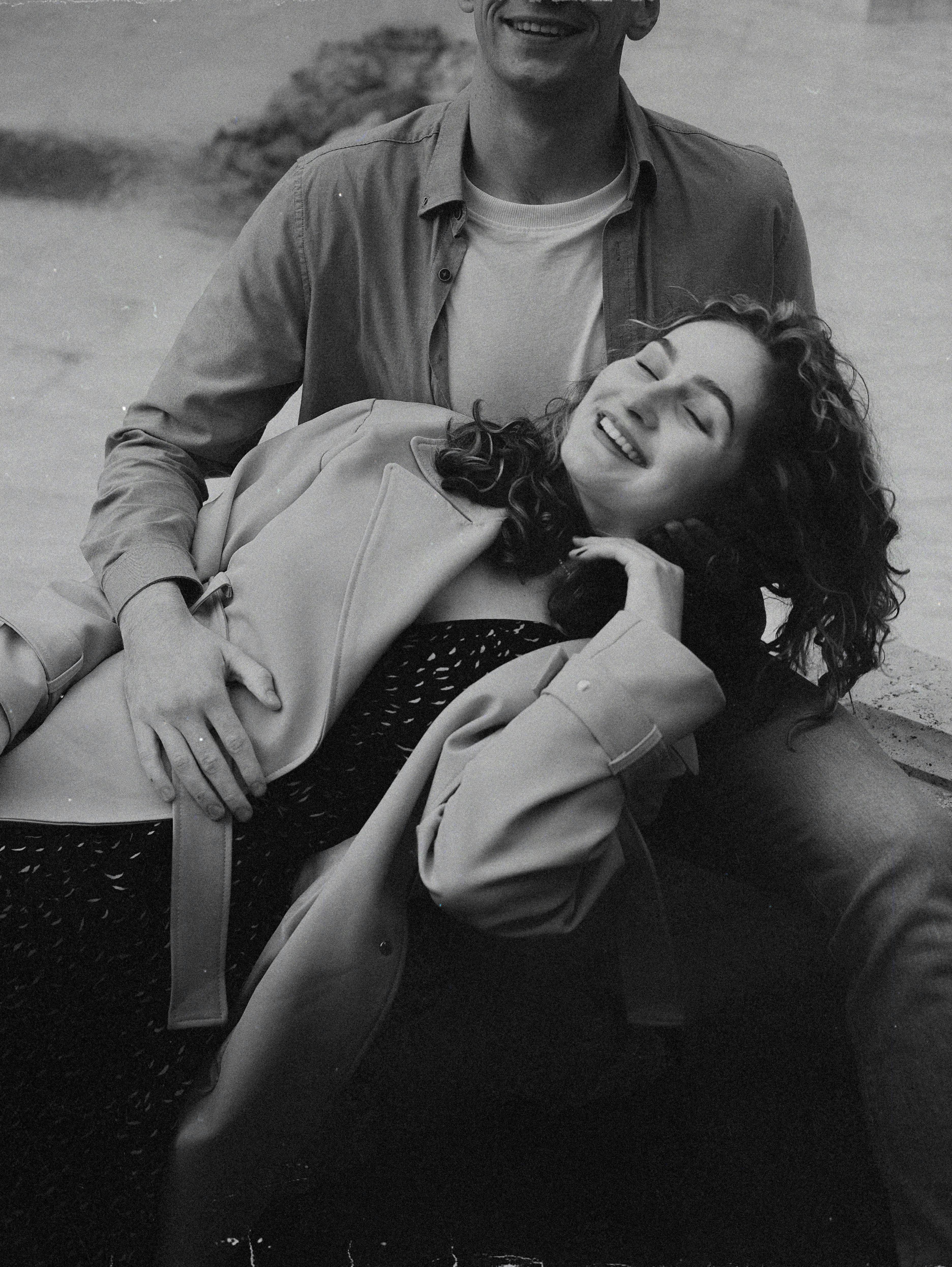 Happy couple embracing outdoors in black and white, showcasing love and relaxation.