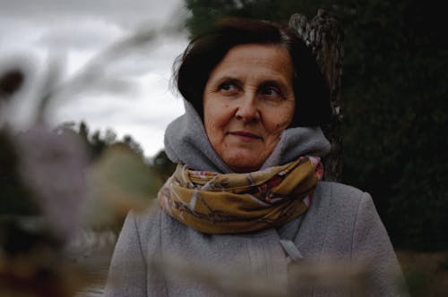 Photo of an Elderly Woman in a Gray Jacket Wearing a Brown Scarf