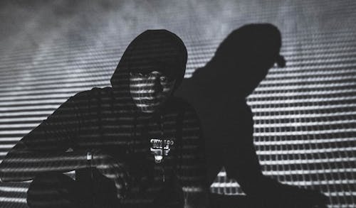 Grayscale Photo of a Man in a Hoodie Wearing a Cap