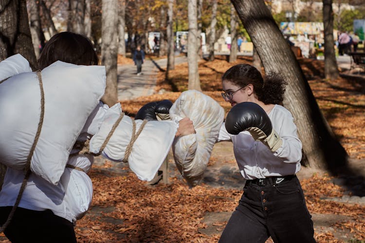 People With Gloves And Pillows Fighting In Park