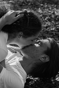 Intimate black and white photo of a young couple kissing outdoors.