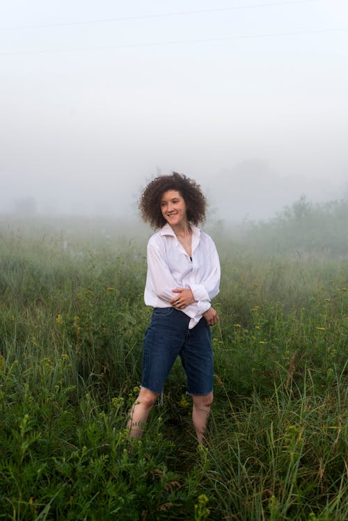 A Woman Standing on a Foggy Field