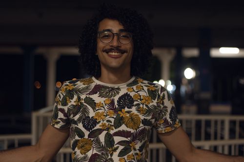 Free Portrait of a man with a floral shirt and mustache smiling at night. Casual and joyful vibe. Stock Photo
