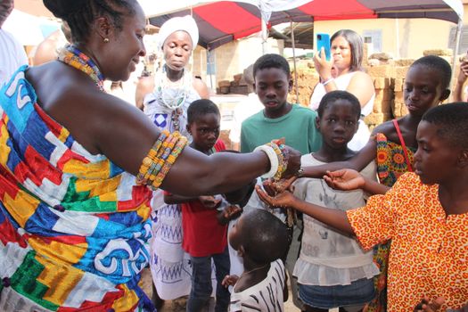 African community celebrating with colorful attire and cultural exchange outdoors.