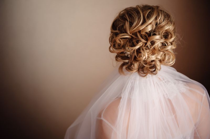 Bridal curly blonde updo hairstyle with a veil