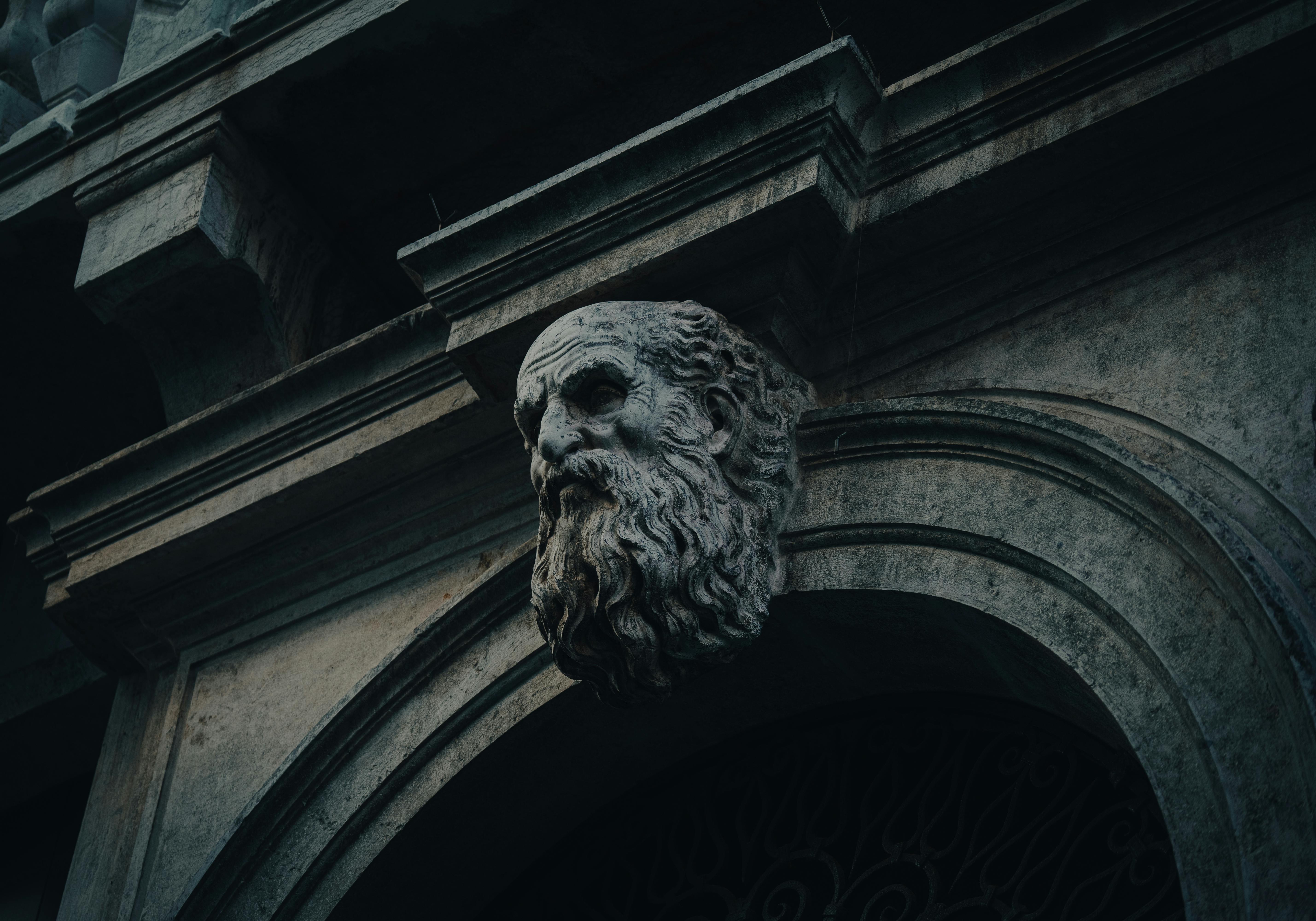 Ancient stone head sculpture on a historic building facade, conveying timeless artistry.