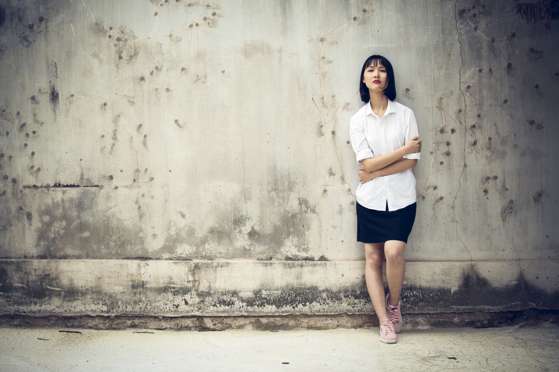 streetwear model in heavy hoodie against concrete wall