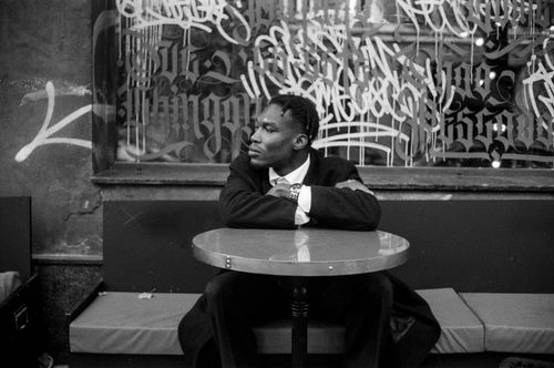 Free A man in a suit sitting at a round table with graffiti in the background, city vibe. Stock Photo