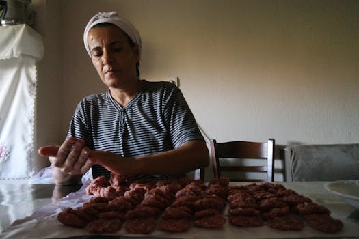 A woman shaping homemade meatballs in a cozy kitchen with soft daylight.
