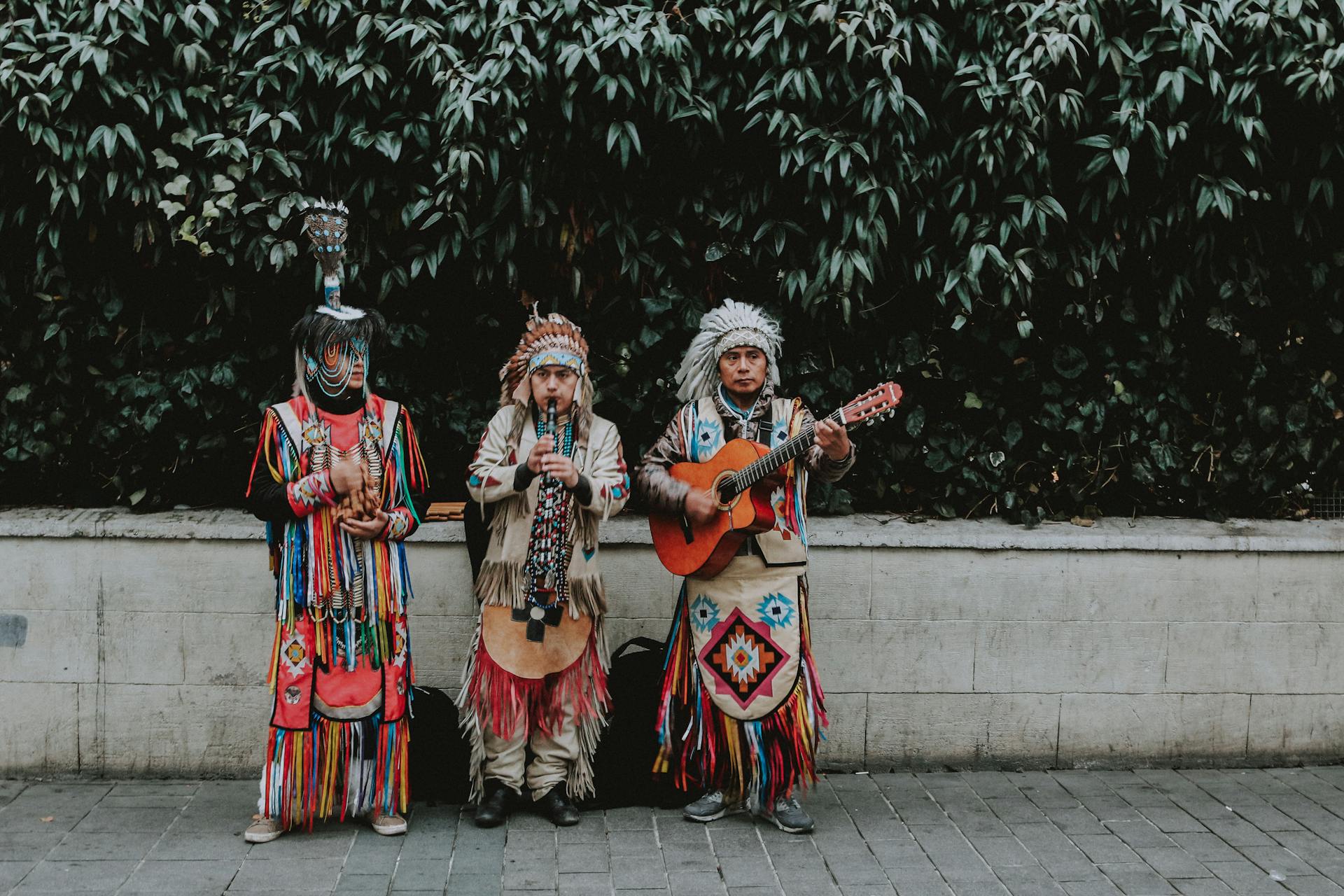 Trois hommes en vêtements traditionnels amérindiens jouent de la guitare sur le bord de la route