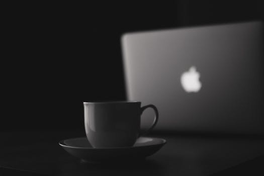 Stylish black and white photo of a coffee cup and laptop, perfect for office-themed concepts.