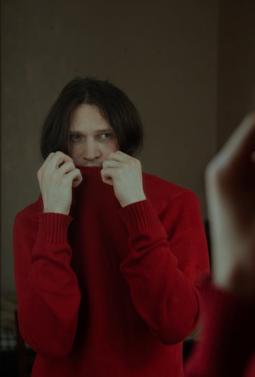 A Man in Red Sweater Looking at the Mirror