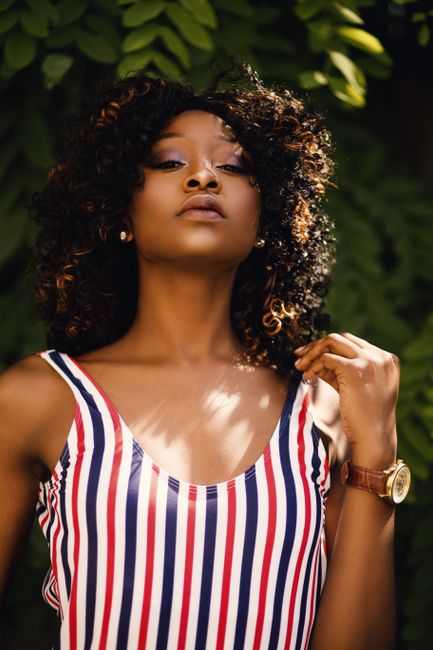 Confident woman in a striped dress poses outdoors, showcasing fashion and elegance.