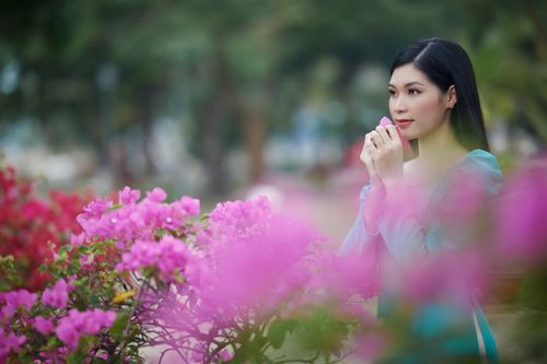 Free A young woman enjoys a peaceful moment surrounded by vibrant pink bougainvillea blossoms. Stock Photo
