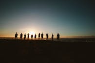 一群朋友站在海滩上，映衬着海上充满活力的日落