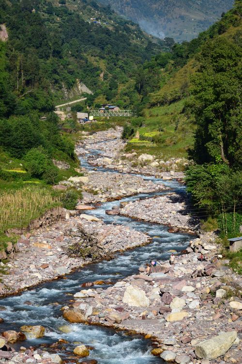 Free Picturesque view of a river cascading through a lush mountain valley with rocks and greenery. Stock Photo