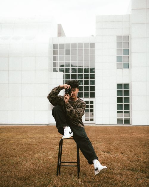 Free Young man photographing in front of a modern building. Creative and stylish outdoor portrait. Stock Photo