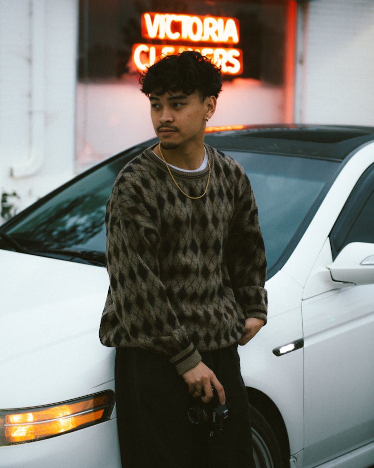 Young Man With Camera Leaning On White Car