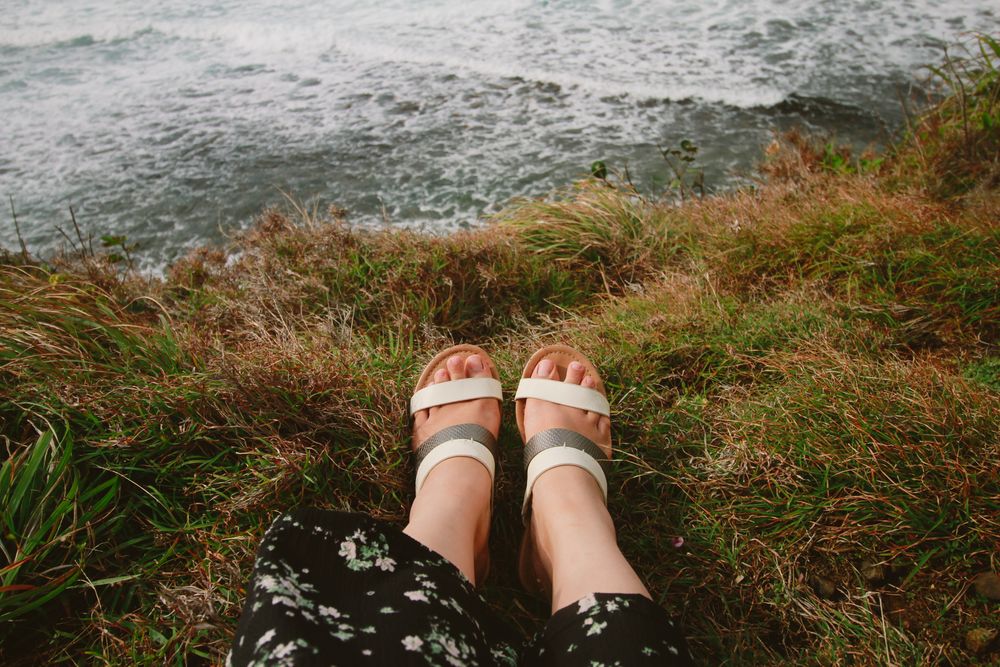 Feet in sandals outdoors near water