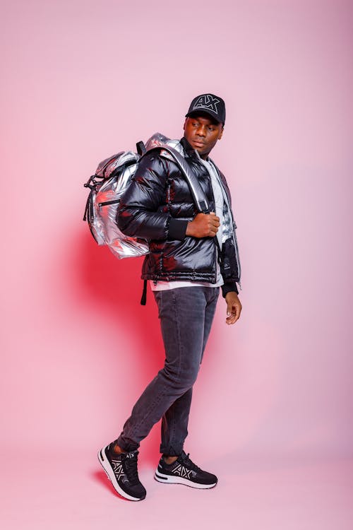 Man Looking Back at Bagpack on Pink Background