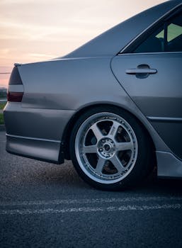 黄昏时分，一辆银色轿车停在路边，露出合金车轮的侧面图
