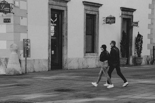 A Man and Woman in Black Jacket Walking on the Street
