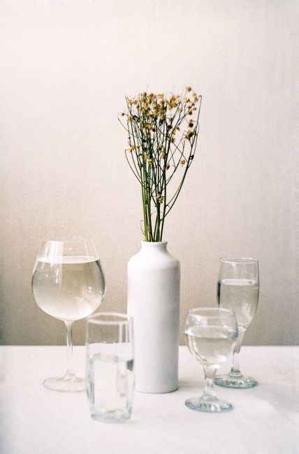 Minimalist still life featuring a white ceramic vase and glassware on a white background.