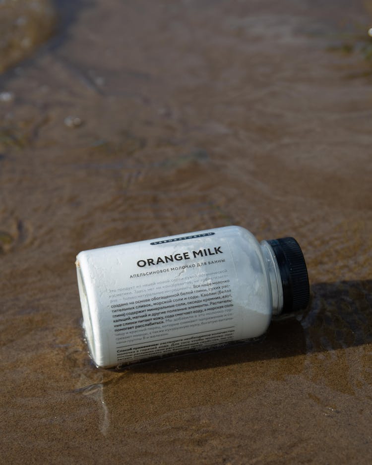 A Product Photography Of Orange Milk Powder In A Bottle