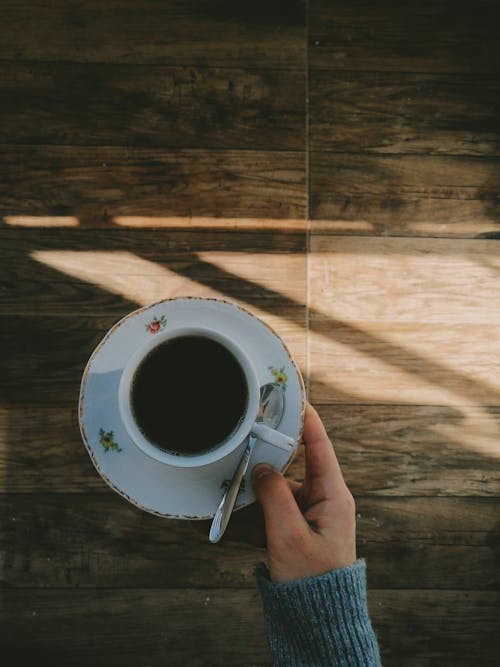 Hand Holding Dish with Coffee Cup