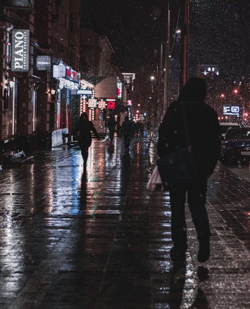 
People Walking on a Sidewalk in a Rainy Day