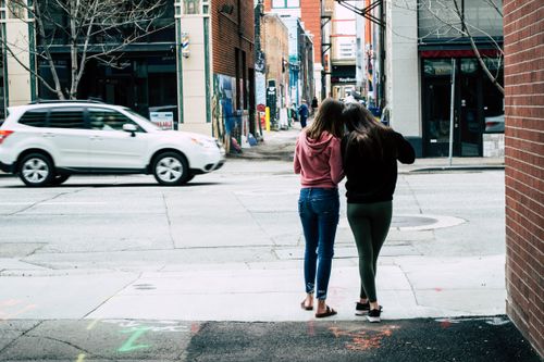 Free Two women walking in an urban alley, capturing city life and architecture. Stock Photo