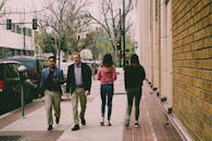 四个成年人白天走在充满活力的城市人行道上