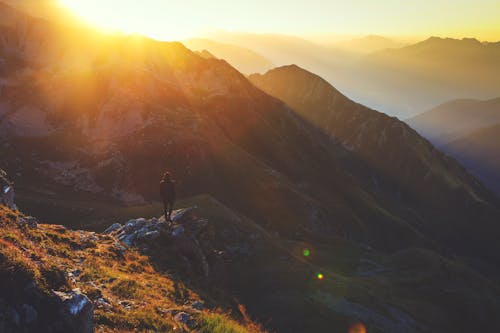 Free Person Standing on Rock Cliff during Golden Hour Stock Photo