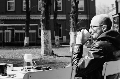 Grayscale Photo of a Man Sitting on a Chair · Free Stock Photo