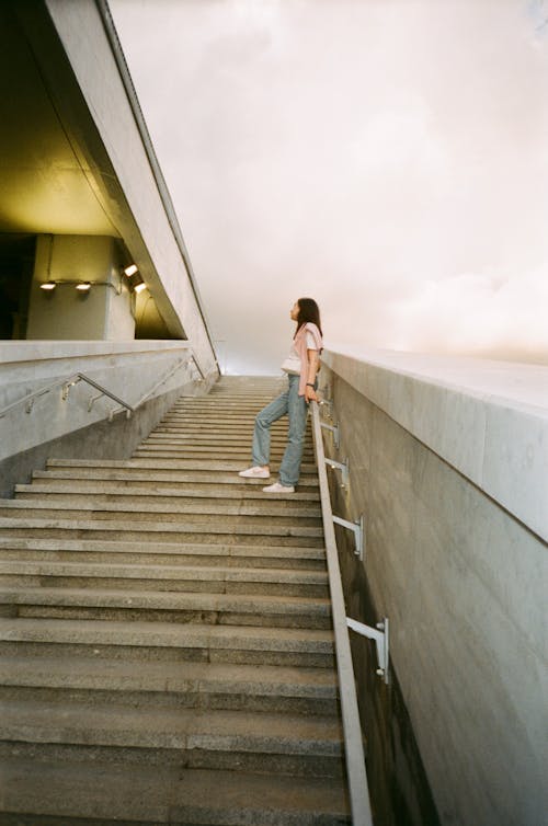 Free Low-Angle Shot of Woman Leaning on Handrail of a Staircase Stock Photo