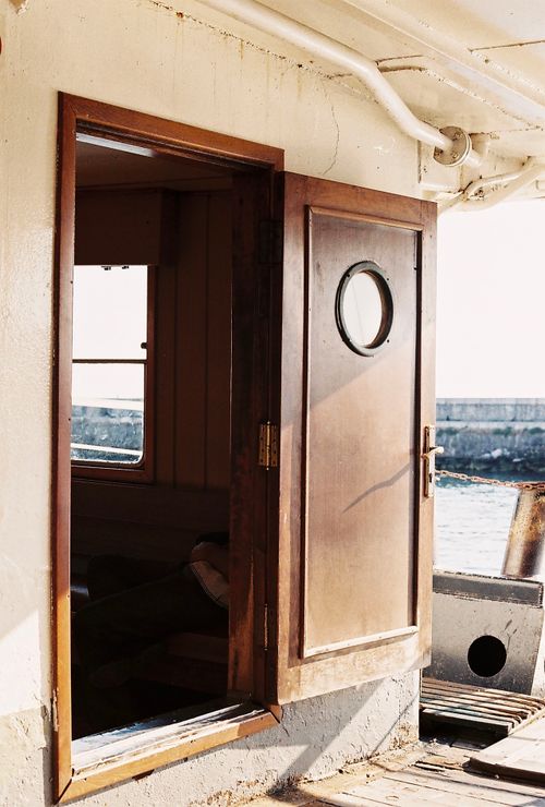 Free An open wooden door leads to the interior of a ship, offering a view of the deck and sea beyond. Stock Photo