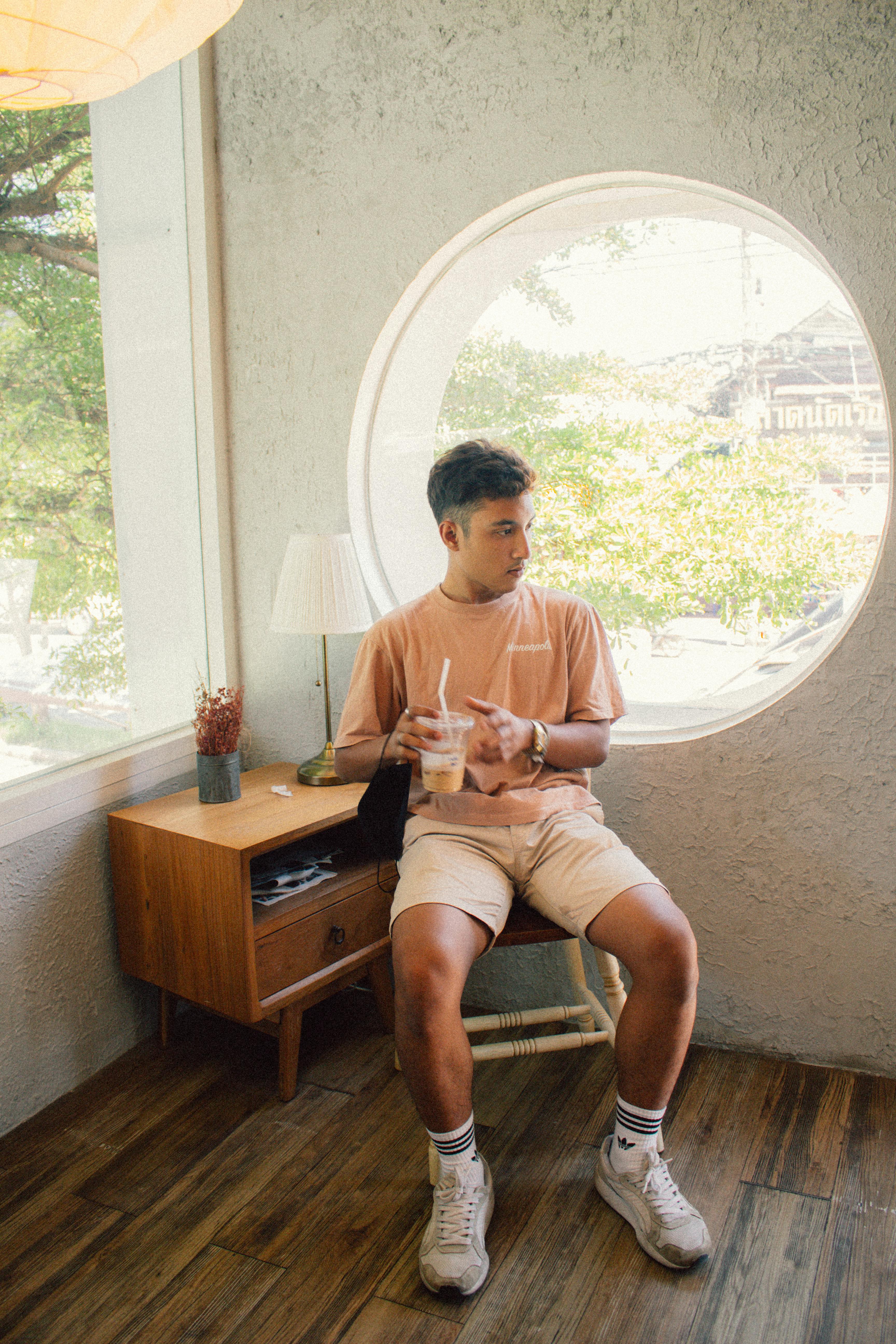 Free Casual young man enjoying a coffee break by the window in a Thai cafe. Stock Photo
