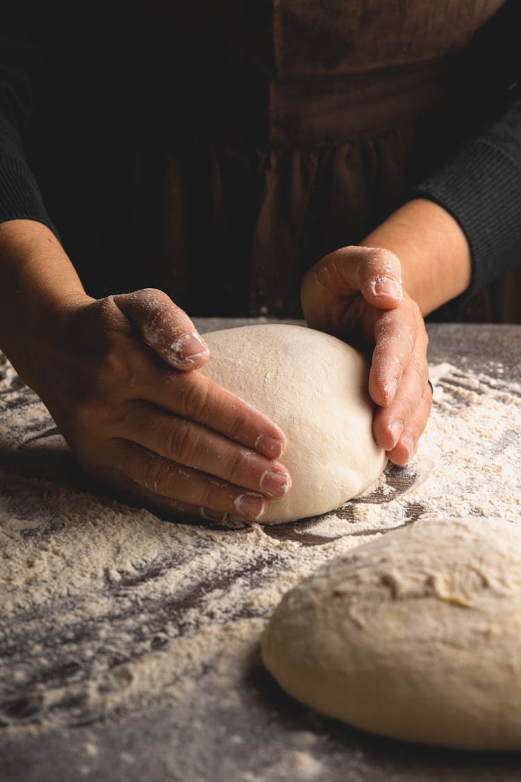 A Person Shaping A Lump Of Dough 