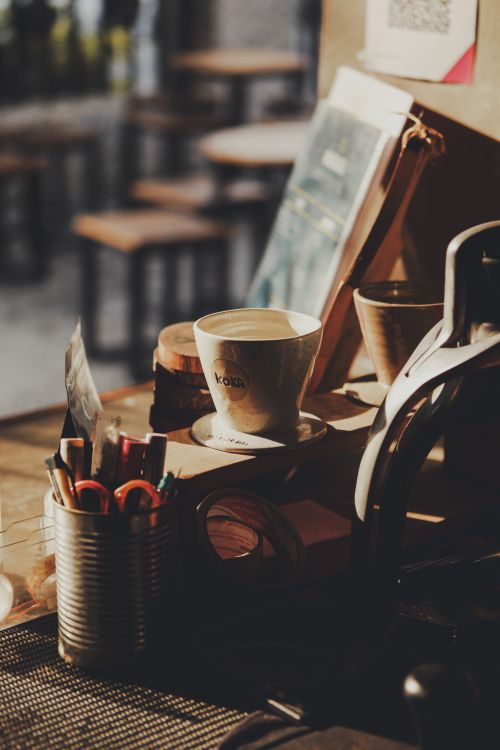 Free Warm, vintage-style café setting with stationery and coffee cup on a desk. Stock Photo