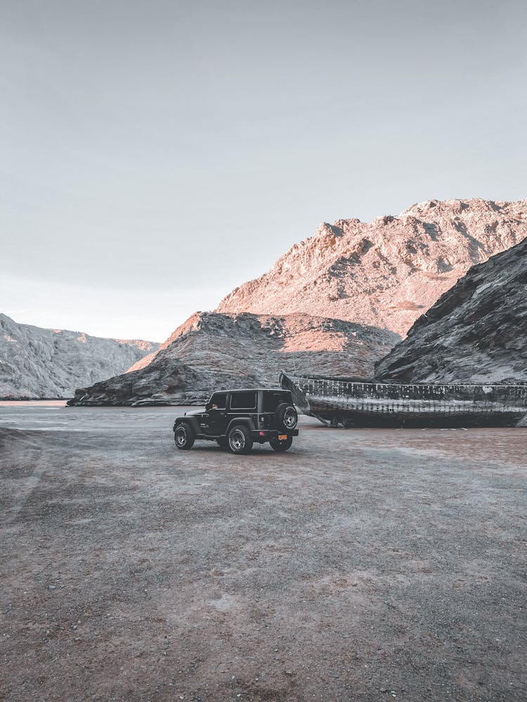 4x4 Car On Dry River Bed Next To Boat