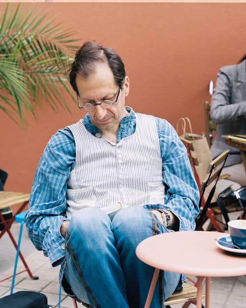 Elderly Man Sitting at Cafe and Reading Book