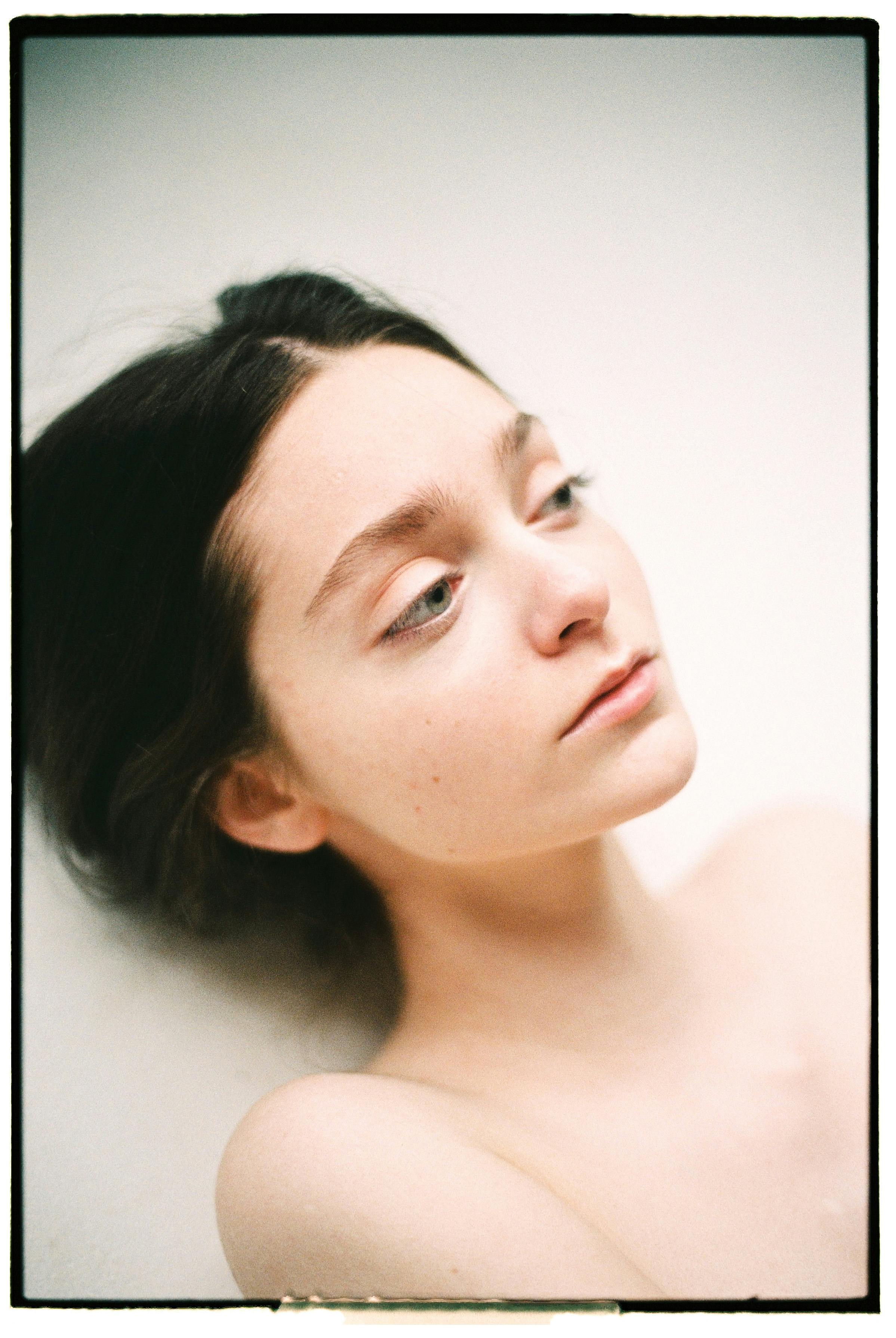Calm portrait of a young woman with black hair and blue eyes lying on her back.