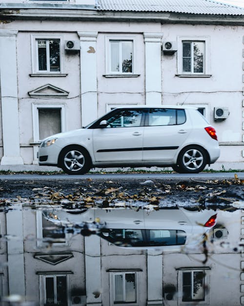 White Sedan Parked Beside White Concrete House