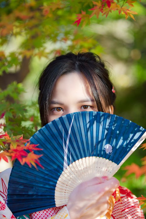 A Woman Covering Her Face With a Blue Fan · Free Stock Photo